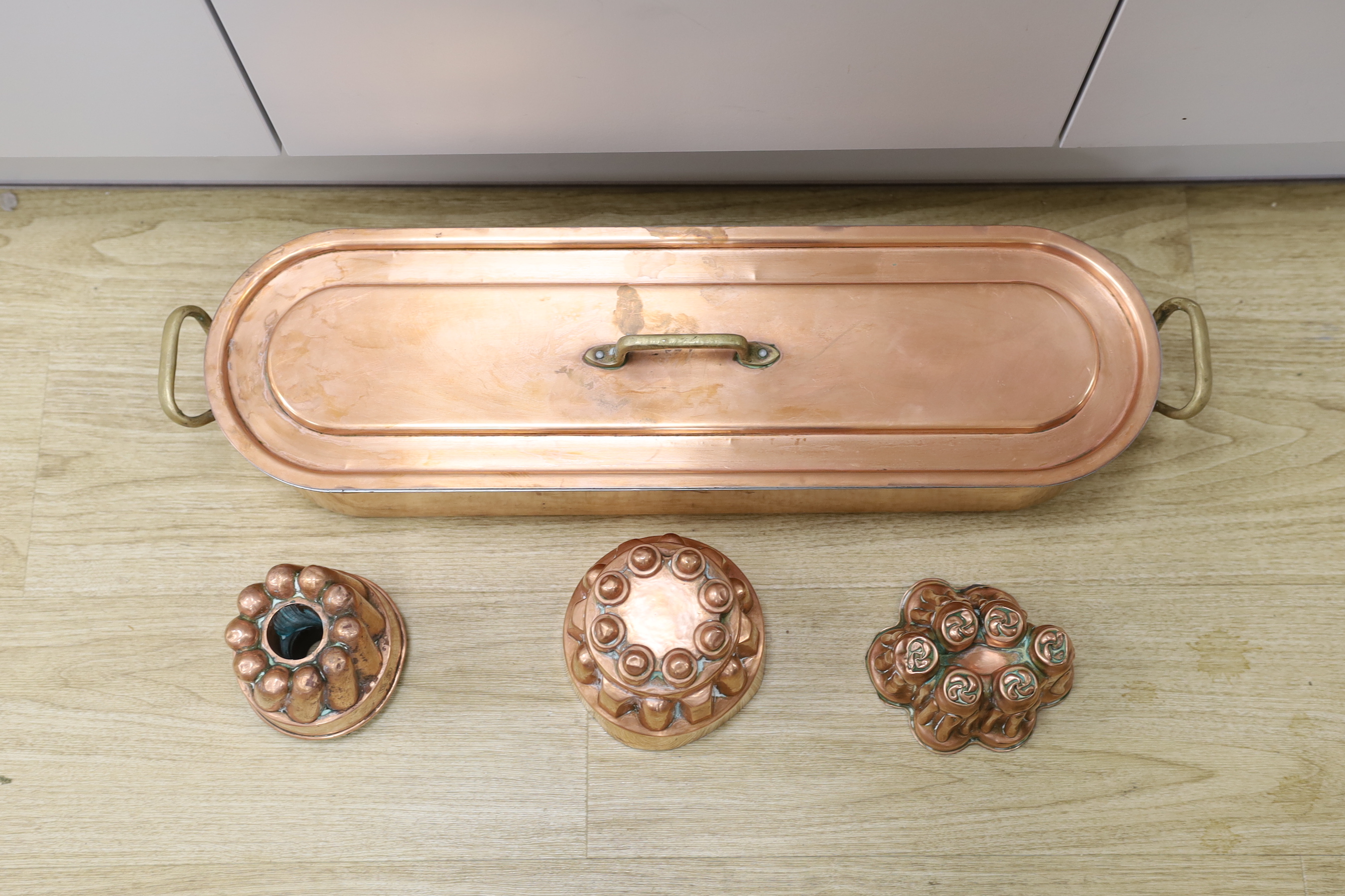 A copper fish kettle and three copper jelly moulds, largest 68.5cm